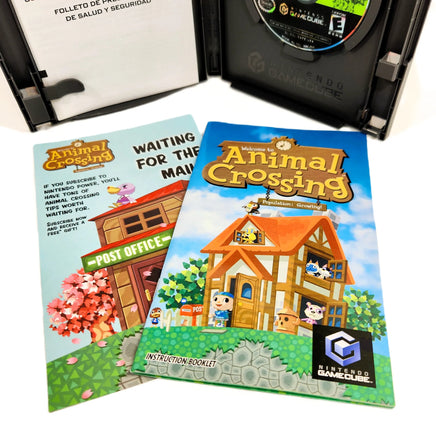 Nintendo GameCube Animal Crossing game case with the game disc visible, shown alongside the instruction booklet and front cover art on a white background.