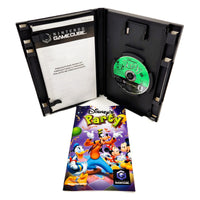 Nintendo GameCube Disney's Party game case shown open with the game disc inside, plus the instruction manual and booklet materials placed in front on a white background.