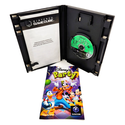 Nintendo GameCube Disney's Party game case shown open with the game disc inside, plus the instruction manual and booklet materials placed in front on a white background.