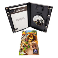 Nintendo GameCube software case for Madagascar, shown open with the game disc inside and the printed instruction manual insert placed in front on a white background.