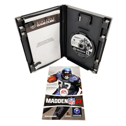 Nintendo GameCube Madden NFL 7 video game shown open with the game disc in the slot, alongside the front cover art of the instruction manual and insert booklet on a white background.