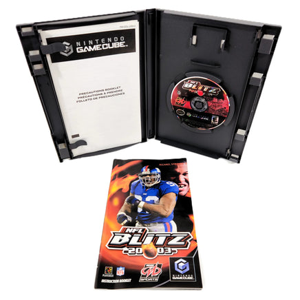 Nintendo GameCube NFL Blitz 2003 video game package shown open with the black GameCube case, game disc, instruction booklet front cover on a white background.