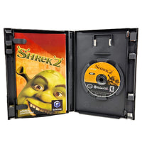 Shrek 2 video game case opened to show the game cover on the left and the disc on the right, photographed on a plain white background.