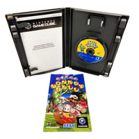Nintendo GameCube 'Super Monkey Ball' game package shown open, with the black plastic game case containing a yellow-and-blue game disc, a printed booklet, and the colorful game instruction manual in front on a white background.