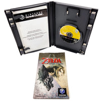 Nintendo GameCube Zelda Twilight Princes game case shown open with the game disc inside, plus the front cover of the instruction manual shown below on a white background.