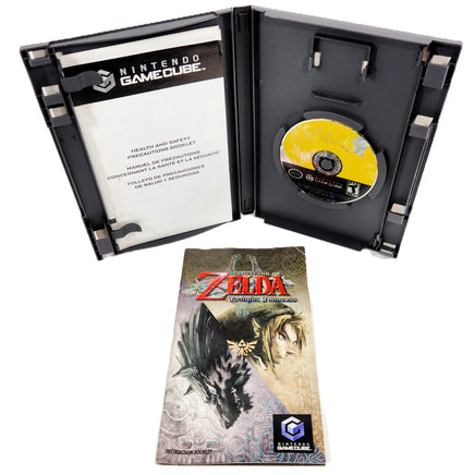 Nintendo GameCube Zelda Twilight Princes game case shown open with the game disc inside, plus the front cover of the instruction manual shown below on a white background.