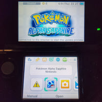 A Nintendo 3DS handheld console showing the Pokémon Alpha Sapphire game menu on the upper screen and the app selection interface on the lower screen.