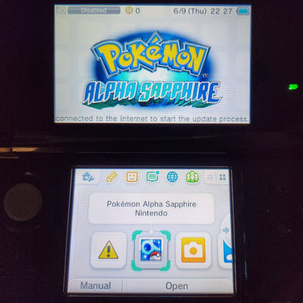 A Nintendo 3DS handheld console showing the Pokémon Alpha Sapphire game menu on the upper screen and the app selection interface on the lower screen.