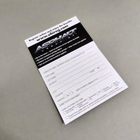 A printed Asphalt Urban GT Games registration card or form for Nintendo DS, photographed at an angle on a neutral gray surface. The card is white with a black header containing the Asphalt Games logo and website, with fields for player name, address, and game title purchased.