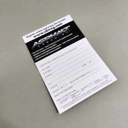 A printed Asphalt Urban GT Games registration card or form for Nintendo DS, photographed at an angle on a neutral gray surface. The card is white with a black header containing the Asphalt Games logo and website, with fields for player name, address, and game title purchased.