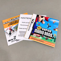 Nintendo New Super Mario Bros. instruction book and manuals for the Nintendo DS, displayed on a neutral gray background.