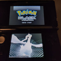 A black Nintendo 3DS handheld game console showing the Pokémon Black Version game menu, with the top screen displaying the Pokémon logo and the bottom screen showing a Pokémon character.