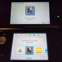 A close-up of a Nintendo 3DS handheld console showing the screen with the Pokémon Conquest Nintendo app open. The top screen displays the app's main interface with a Pokémon portrait, and the bottom screen shows app icons including a warning icon, the portrait, a camera icon, and an 'Open' label.