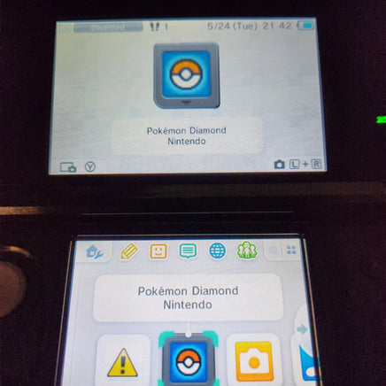 A close-up of a Nintendo DS game screen showing the Pokémon Diamond and Nintendo app icon, with the DS hardware partially visible in a dark setting.