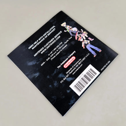 Rear view of Nintendo DS Pokémon Diamond Version instruction booklet featuring game character illustrations on a dark background, photographed on a light gray surface.