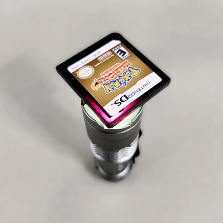 Pokémon HeartGold Version [NFR] Nintendo DS - Close-up authenticity detail of Pokémon DS cartridge showing reddish-purple translucency under light, like new condition