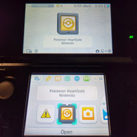 A close-up of a Nintendo 3DS handheld console screen showing the Pokémon HeartGold app interface, with the Pokémon HeartGold icon displayed on the screen and the game card selected in the menu.