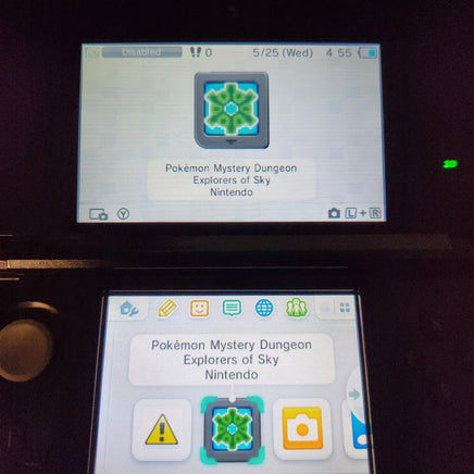 A close-up of a Nintendo 3DS handheld console showing two game screens. The top screen displays a 'Pokémon Mystery Dungeon: Explorers of Sky' icon, and the bottom screen shows the app menu with the selected icon highlighted.