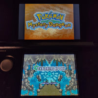 A Nintendo 3DS game console displaying the Pokémon Mystery Dungeon Explorers of Sky game menu, with the top screen showing the Pokémon logo and the bottom screen showing the Explorers of Sky Press Start screen.