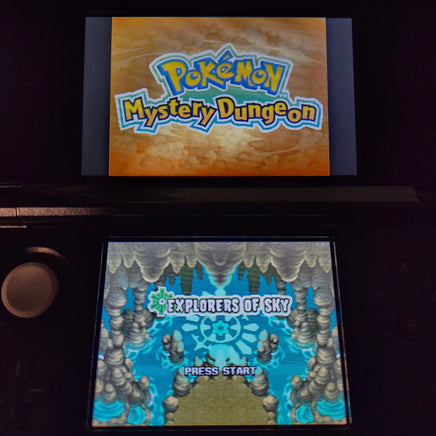 A Nintendo 3DS game console displaying the Pokémon Mystery Dungeon Explorers of Sky game menu, with the top screen showing the Pokémon logo and the bottom screen showing the Explorers of Sky Press Start screen.