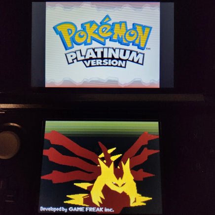 A Nintendo 3DS handheld game console displaying the Pokémon Platinum Version game screen, with the Pokémon logo on the top screen and a stylized yellow and red dragon-like character on the bottom screen.