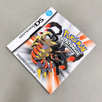 Nintendo DS game instruction manual for Pokémon Platinum Version featuring a gold and black metallic dragon-like Pokémon on a white and orange burst background, photographed on a neutral gray surface.