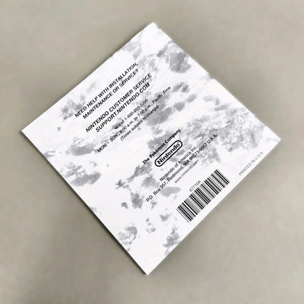 Rear view of Nintendo DS game instruction manual for Pokémon Platinum Version, photographed on a neutral gray surface.