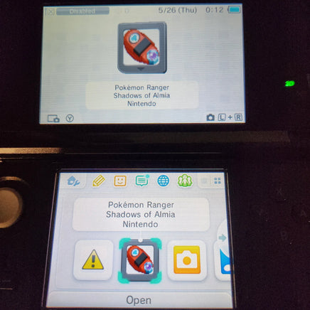 A Nintendo 3DS handheld console showing the Pokémon Ranger Shadows of Almia Nintendo app on both the upper screen and the lower screen, photographed in a dark setting.