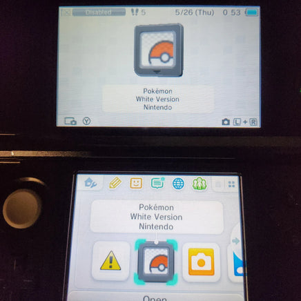 A close-up of a Nintendo 3DS handheld console showing the Pokémon White Version Nintendo game app on the screen, with the Pokémon logo icon highlighted.
