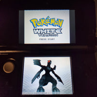 A Nintendo 3DS handheld game console displaying the Pokémon White Version main menu on the upper screen and a character cutout on the lower screen.
