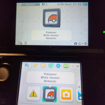 A close-up of a Nintendo 3DS handheld console showing the Pokémon White Version app on the screen, with the Pokémon logo icon highlighted.