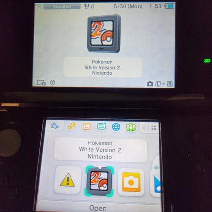 A close-up of a Nintendo 3DS handheld console showing the Pokémon White Version 2 game menu on the screen, with the top and bottom display showing game icons.
