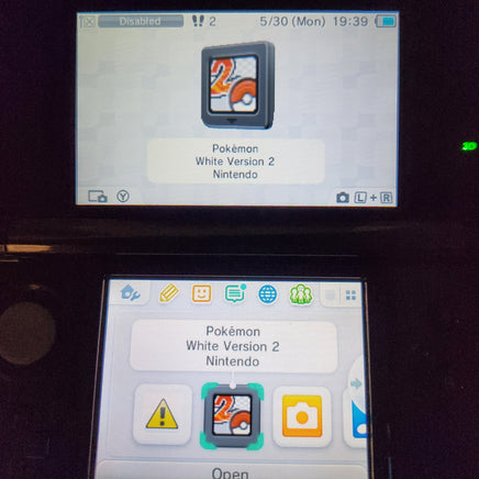A close-up of a Nintendo 3DS handheld console screen showing the Pokémon White Version 2 game cartridge icon, with the Pokémon logo visible on the upper screen and the game icon selected in the lower screen's app grid.