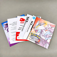 A set of Nintendo DS instruction manuals and pamphlets fanned out on a neutral gray surface. Visible items include a Pokémon White Version 2 instruction booklet, a white Nintendo DS booklet, a Club Nintendo membership card, and other colorful game papers.