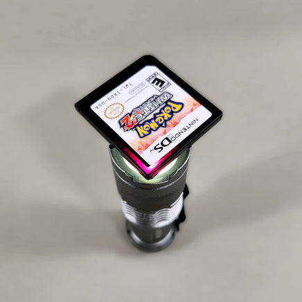 Pokémon White Version 2 for Nintendo DS - Nintendo DS IR cartridge held against a light source to show its reddish-purple translucent shell, very good condition, loose