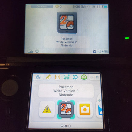 A Nintendo 3DS handheld console showing the Pokémon White Version 2 game interface on both the top screen and the lower screen, photographed in a dark setting.