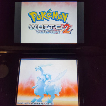 Nintendo DS console showing the Pokémon White Version 2 game screen, with the Pokémon logo on the upper display and a blue pokemon character on the lower screen.