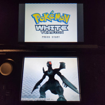 A Nintendo DS game screen showing the Pokémon White Version main menu, with the Pokémon logo on the upper screen and a dark Pokémon character on the lower screen.