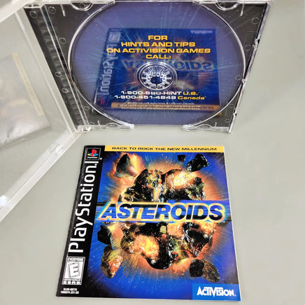 Asteroids for PlayStation 1 - Disc removed to show artwork behind disc tray with front of instruction manual shown, like new condition